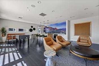 A modern living room with a large painting on the wall and a long black couch.